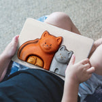 A close up of a child's hands holding the PlanToys Cat Puzzle.