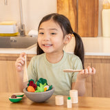Child sitting at the table with a PlanToys chef salad bowl full of loose play food