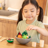 Child playing with the PlanToys chef salad bowl full of loose play food at the table