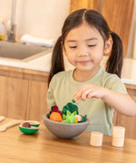 Child playing with the PlanToys chef salad bowl full of loose play food at the table