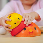 A close up of a child's hands playing with the PlanToys Chicken Nesting Toy. 