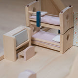 The bunk beds and the writing desk from the Plan Toys Children's Room Dolls House Furniture Set placed in a room in a dolls house. 

