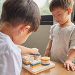 Close up of two young boys playing with the PlanToys geometric orchard shape sorting toy on a wooden table