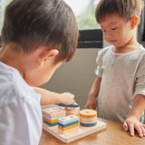 Close up of two young boys playing with the PlanToys geometric orchard shape sorting toy on a wooden table