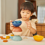 Young child stacking the PlanToys wooden orchard sort and count cups on a table