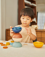 Young child stacking the PlanToys wooden orchard sort and count cups on a table
