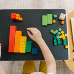 Close up of a child's hands sorting the PlanToys rainbow coloured counting cubes on a black table