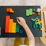 Close up of a child's hands sorting the PlanToys rainbow coloured counting cubes on a black table