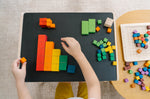 Close up of a child's hands sorting the PlanToys rainbow coloured counting cubes on a black table