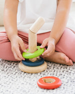 Close up of child's hands sliding green disc onto the PlanToys twist and sort game