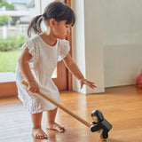 Girl reaching down to grab the PlanToys wooden climbing gorilla pull along toy