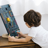 Child leaning over and drawing with a chalk on the PlanToys wooden wall ball game board