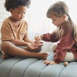 playing with the PlanToys sensory touch and guess game on a grey sofa