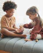 playing with the PlanToys sensory touch and guess game on a grey sofa