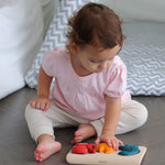 A child playing with PlanToys Dino Puzzle, child is sat on the floor. 