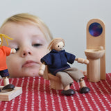 A child playing with peg dolls and the PlanToys classic natural wooden dollshouse bathroom furniture.