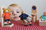 A child playing with peg dolls and the PlanToys classic natural wooden dollshouse bathroom furniture.