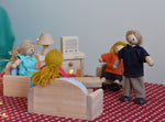 A play scene including PlanToys peg dolls sitting in their natural wooden living room furniture