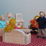 A play scene including PlanToys peg dolls sitting in their natural wooden living room furniture