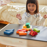 A child sat at the PlanToys desk playing with the PlanToys Coloured Fraction Blocks set. 