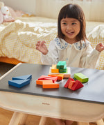 A child sat at the PlanToys desk playing with the PlanToys Coloured Fraction Blocks set. 