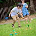 Two children playing with the PlanToys Croquet set outdoors. 