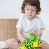 Close-up of a toddler playing with the Plan Toys Dancing Alligator wooden pull along toy