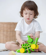 Close-up of a toddler playing with the Plan Toys Dancing Alligator wooden pull along toy