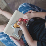 A view from above of a child playing with the PlanToys dog wooden puzzle toy. 