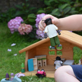A child holding a doll from the PlanToys doll house family set in their hand.
