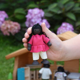 A child holding a doll from the PlanToys doll house family set in their hand.