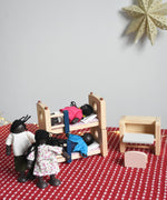 The PlanToys Dolls House Family with Black Skin and Black Hair set up in a scene with the PlanToys dolls house furniture.