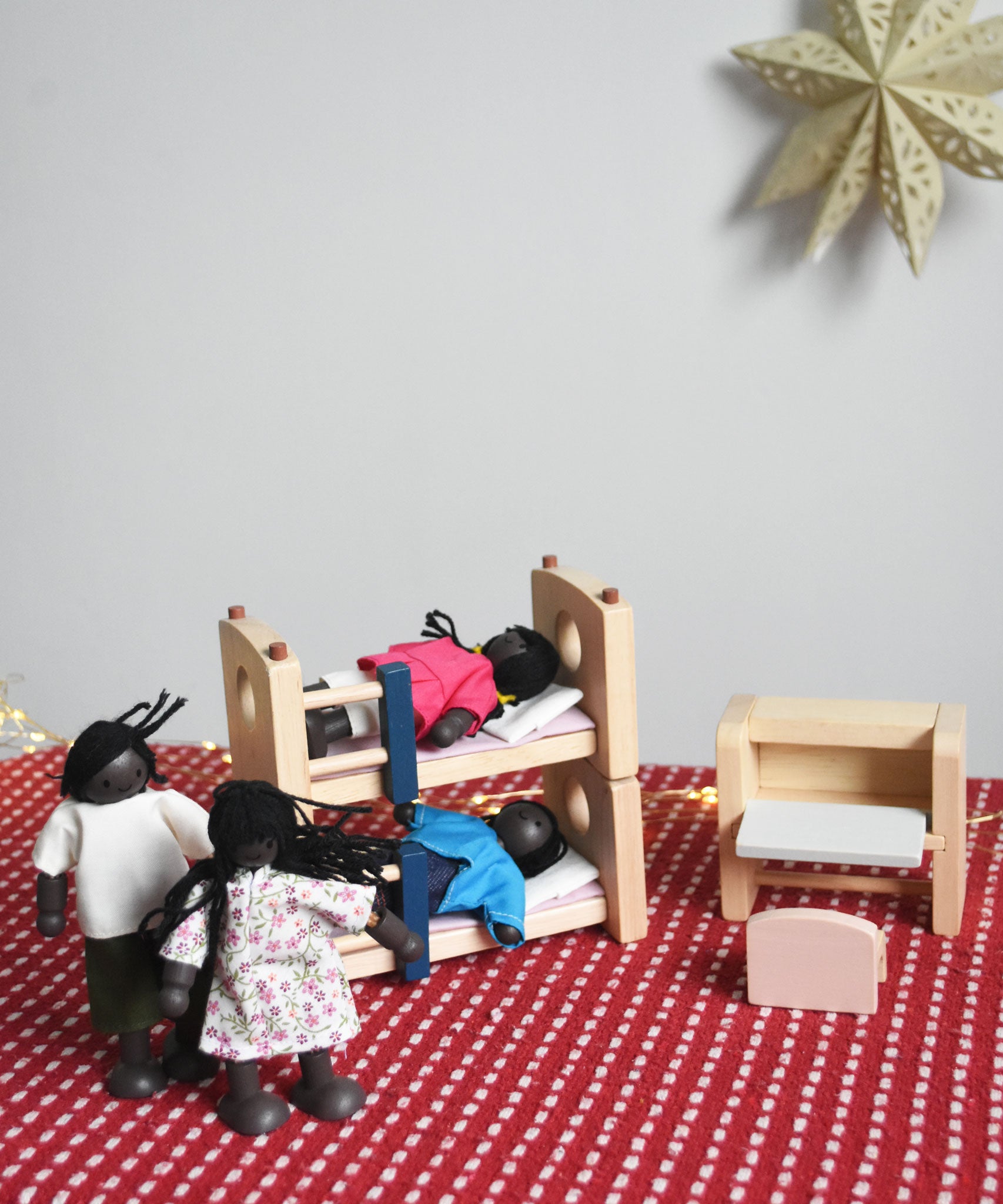 The PlanToys Dolls House Family with Black Skin and Black Hair set up in a scene with the PlanToys dolls house furniture.