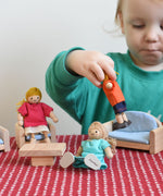 A child playing with the PlanToys Dolls House Family withWhite Skin, Blonde Hair and PlanToys dolls house furniture.