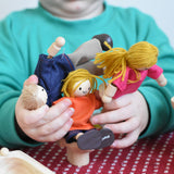 A child holding the PlanToys Dolls House Family with White Skin, Blonde Hair in their hands.