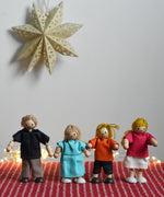 The PlanToys Dolls House Family with White Skin, Blonde Hair placed in a standing position and placed on a red blancket.