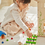 A child playing with the PlanToys Dolls House Vegetable Garden set. 