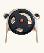 PlanToys Driving Console wooden toy. Black steering wheel with orange button in the middle on a wooden dashboards with wing mirrors.