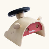 PlanToys Driving Console wooden toy. Black toy steering wheel on a wooden dashboard with wing mirrors.
