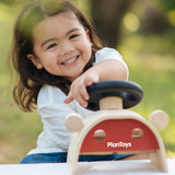 Child turning the steering wheel on the PlanToys Driving Console wooden toy.