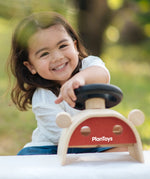 Child turning the steering wheel on the PlanToys Driving Console wooden toy.