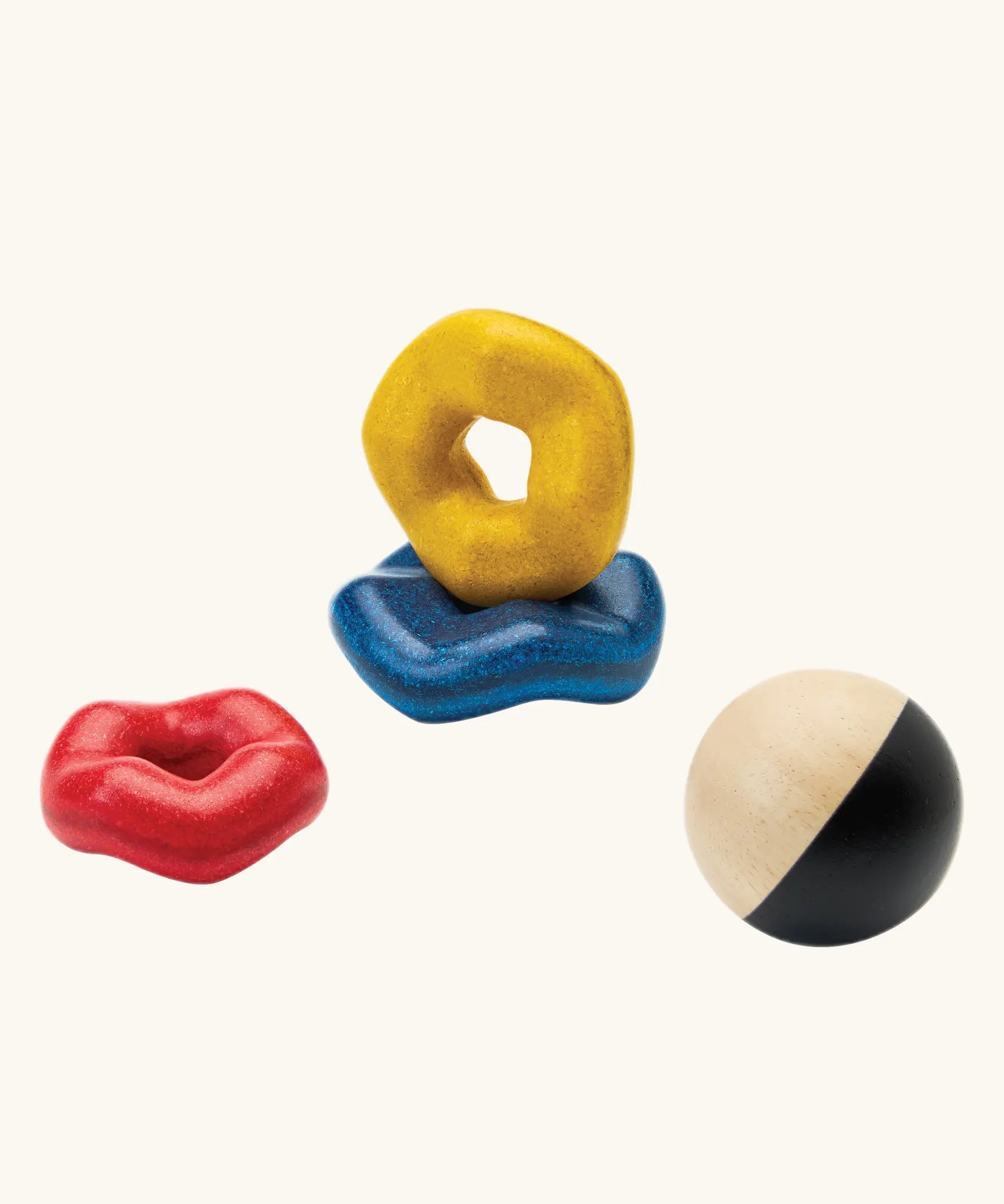 PlanToys wave ball stacker wooden stacking toy. Blue, yellow and red wavy rings with a black and white ball. 