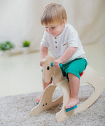 A child rocking on the PlanToys Palomino Rocking Horse. 