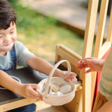 Child handing over a basket full of wooden PlanToys eggs 