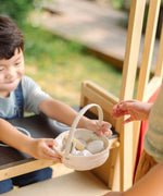 Child handing over a basket full of wooden PlanToys eggs 