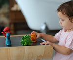 A child playing with the PlanToys Dino Set on a PlanToys desk. 
