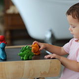 A child playing with the PlanToys Dino Set on a PlanToys desk. 