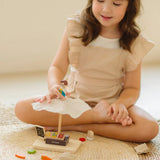 Child playing with the PlanToys Farmer's Market wooden toy playset. Child placing the worker wooden figure on the market stall canopy.