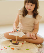 Child playing with the PlanToys Farmer's Market wooden toy playset. Child placing the worker wooden figure on the market stall canopy.