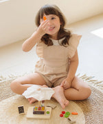 Child playing with the PlanToys Farmer's Market wooden toy playset holding a toy carrot in her hand. 